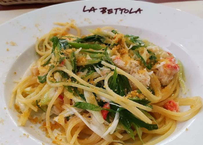 A pasta dish served at La Bettola da Ochiai, featuring onions, seafood, and parmesan.